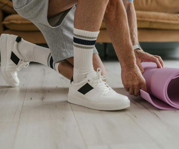 Person rolling out a yoga mat on a wooden floor.
